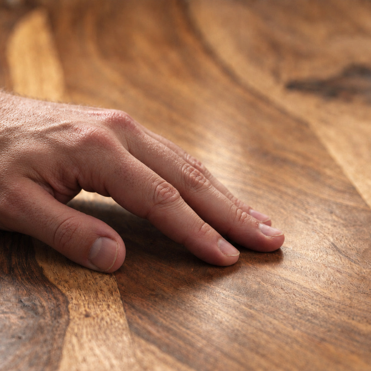 Männerhand prüft die samtige Haptik einer mit OLI NATURA Möbelwachs behandelten Holzoberfläche.